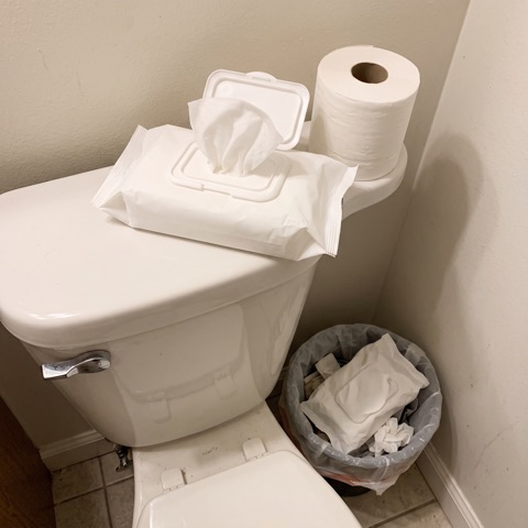 An open pack of wet wipes on the toilet tank